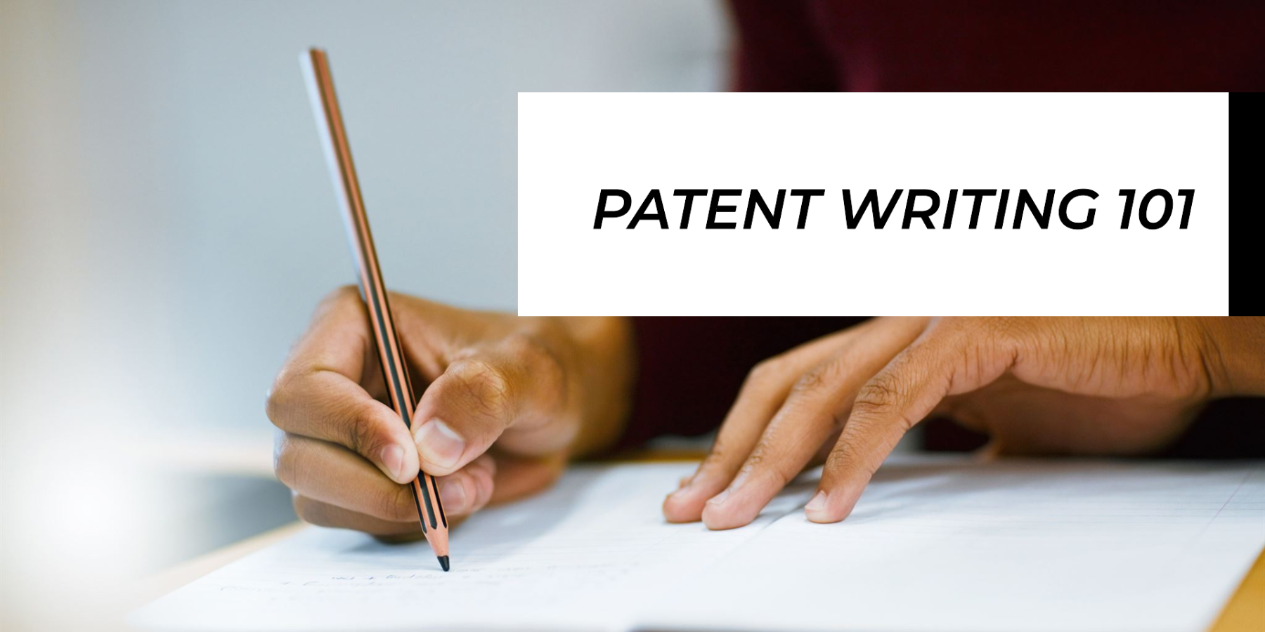 a person writing a patent holding a pencil
